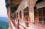Maijishan Shiku (Maiji Shan Grottoes) are one of China’s four most important Buddhist temple groups (the others being Datong, Luoyang, and the Mogao Caves at Dunhuang).<br/><br/>

Starting from the Northern Wei (386-535) and Northern Zhou (557-81) Dynasties, Buddhists cut caves into the sides of a red outcrop rising from the surrounding foliage-covered hills. Figures of the Buddha, of bodhisattvas and disciples were carved in harder rock brought from elsewhere, and installed in the caves.<br/><br/>

At their height, the Maijishan caves are believed to have numbered almost 800, but they suffered serious damage during an earthquake in 734. This event, combined with the exigencies of time, has reduced the number of extant caves to 194.<br/><br/>

The existing rock cut architecture contains over 7,200 Buddhist sculptures and over 1,000 square meters of murals.<br/><br/>

Maiji Shan translates literally as 'Wheatstack Mountain'.